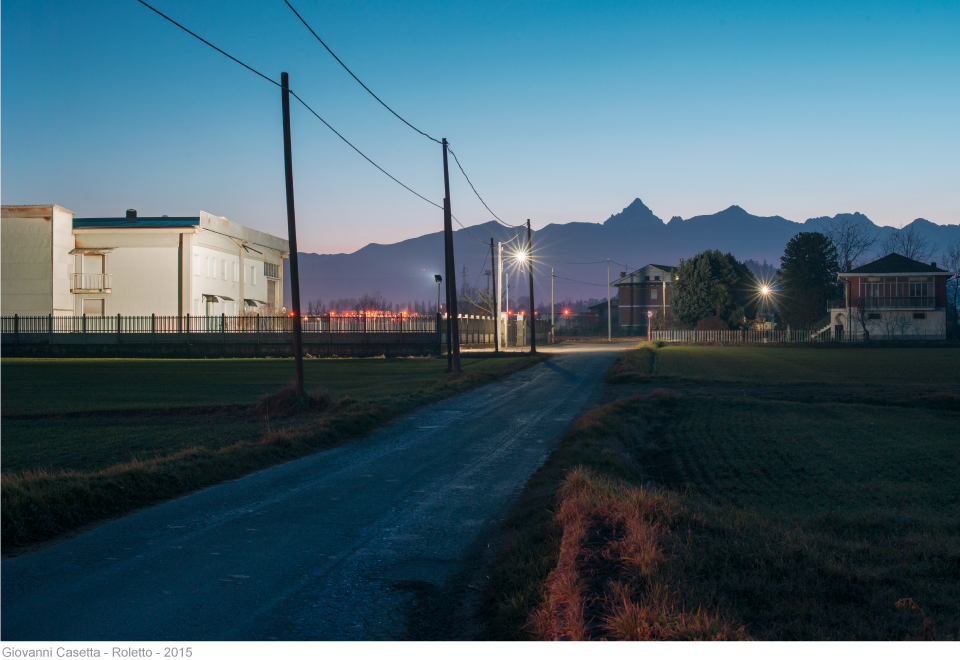 Roletto, notte, fabbrica e casa in primo piano e Monviso sullo sfondo