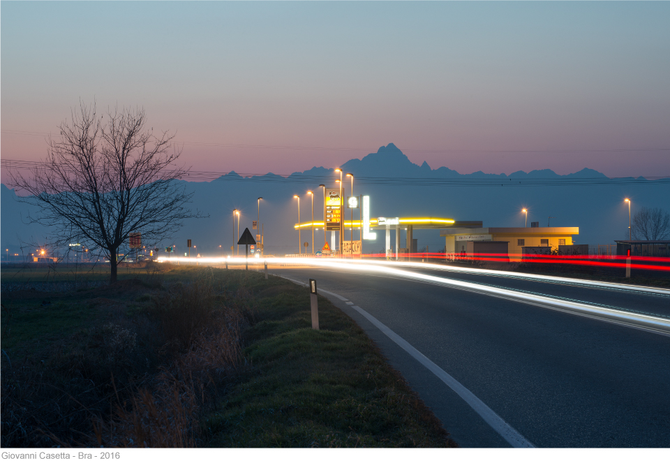 Bra, notte, strada, fari delle auto, distributore benzina, sullo sfondo il Monviso